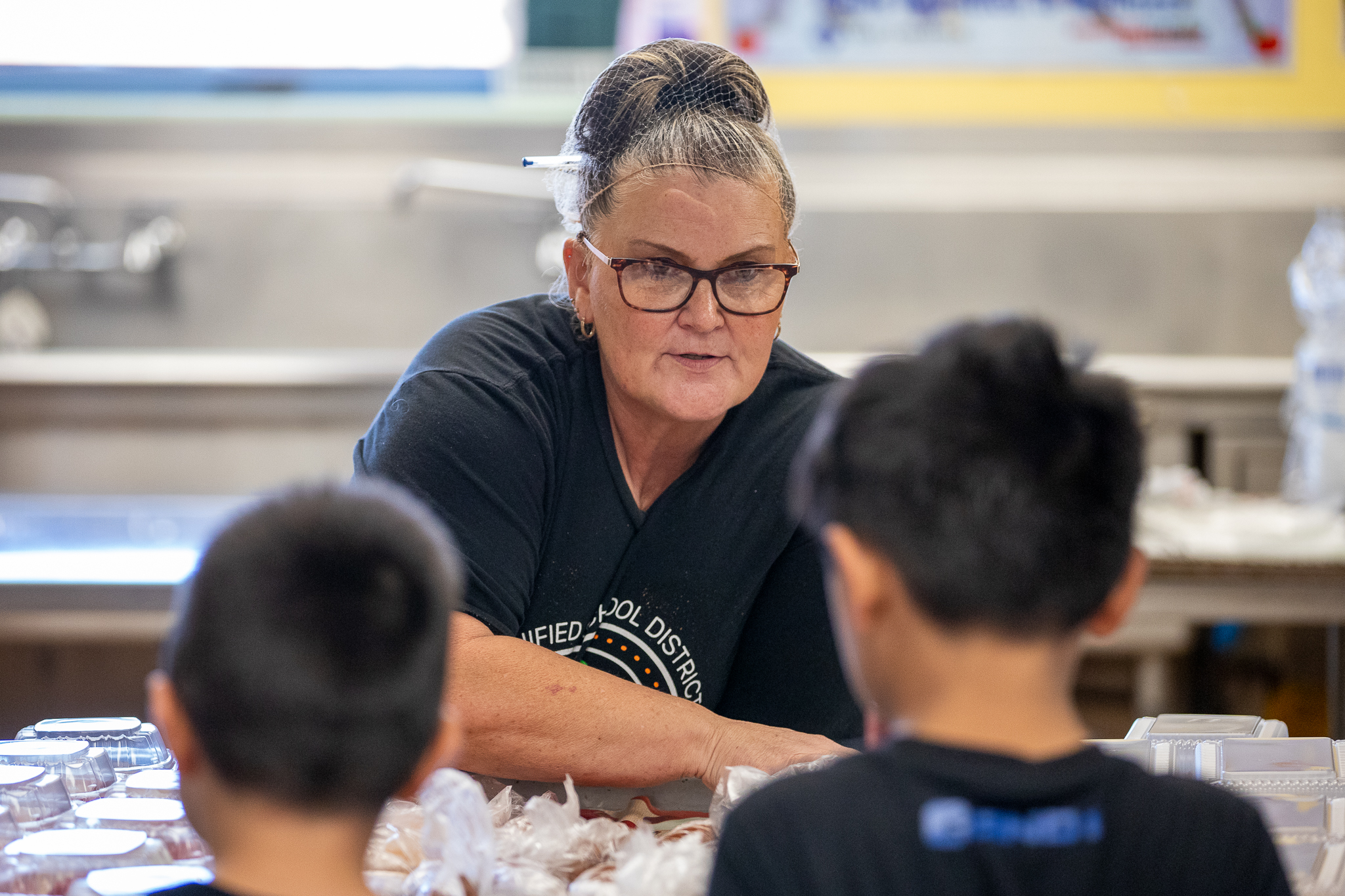 A Food Services worker hands smiles as she hands students their lunch