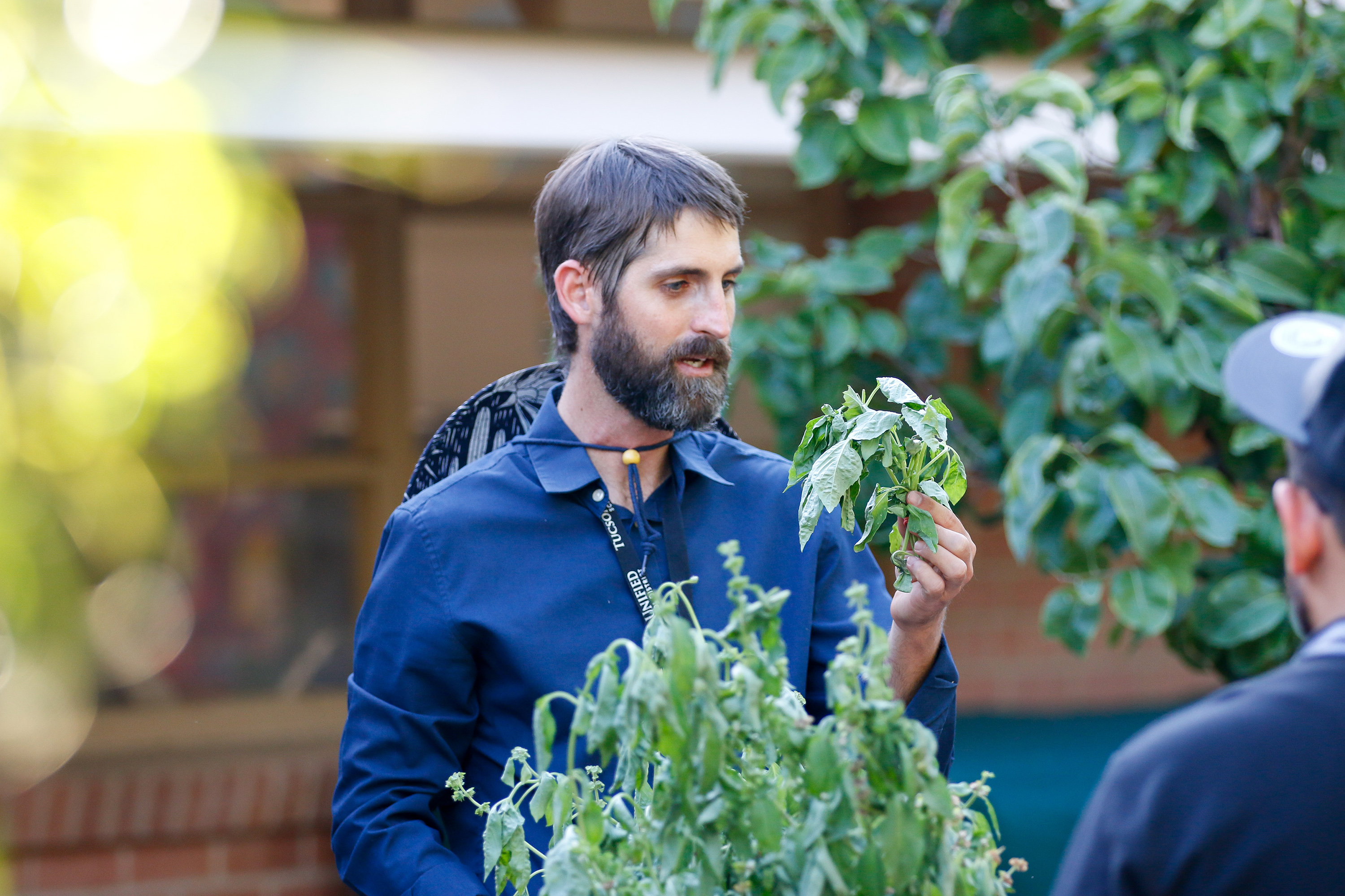 The gardening teacher holds up some plants outside in the garden