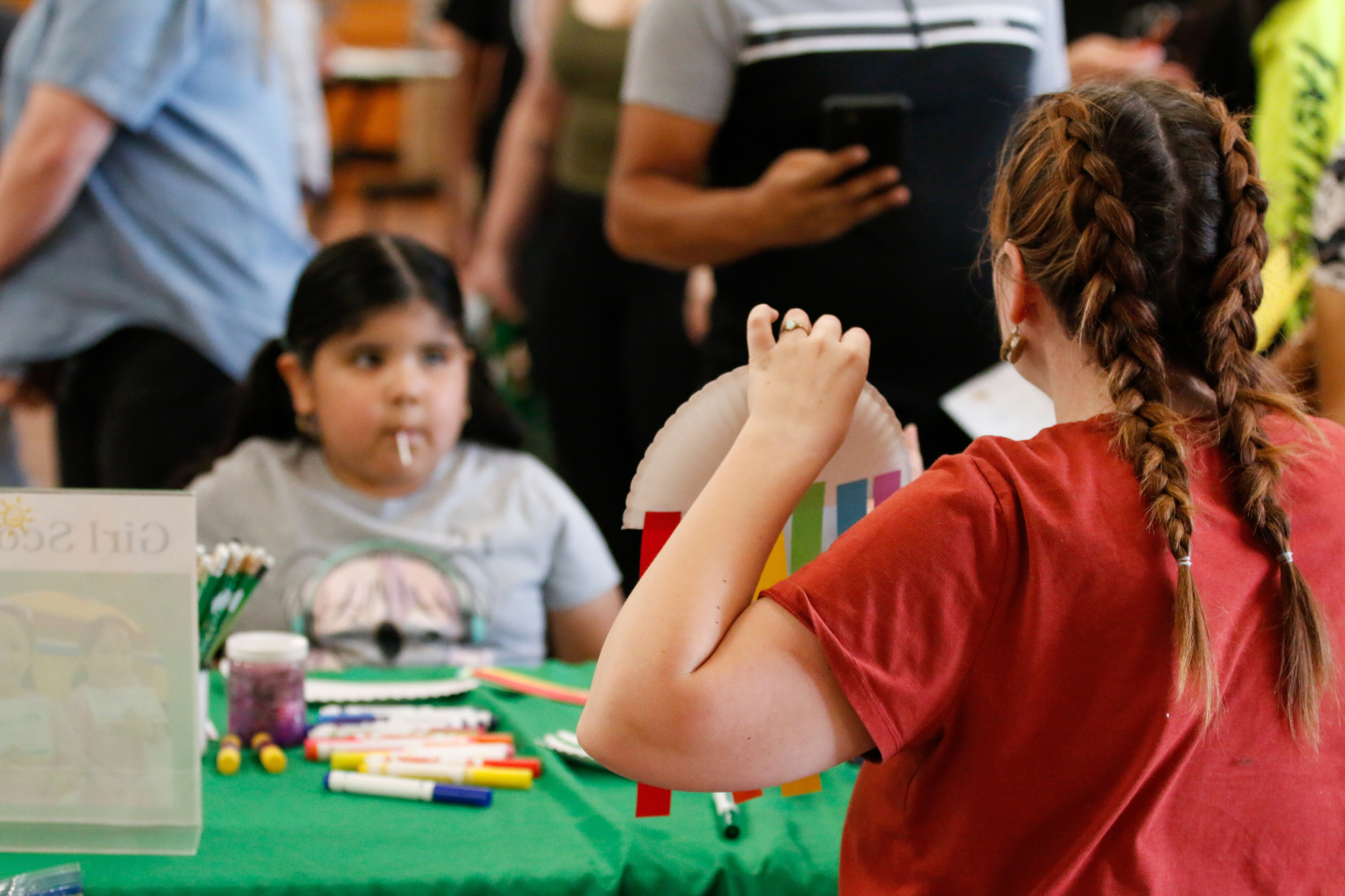 A little girl watches a demonstration on how to put together a craft