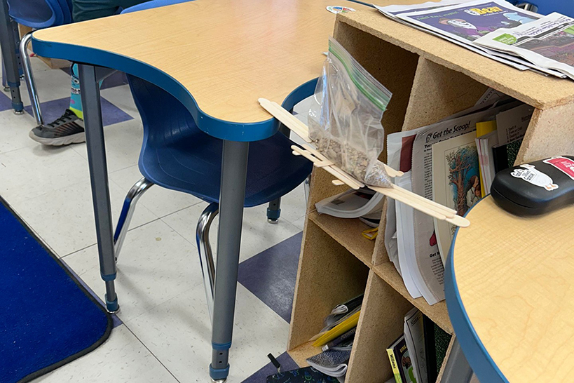 A bridge made of popsicle sticks between two desks