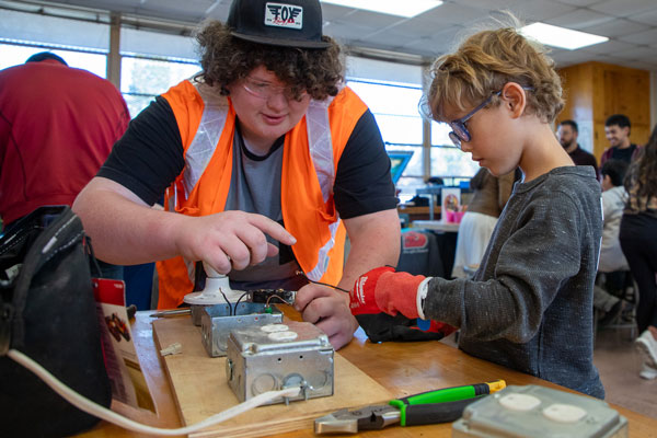 A child learns hands-on electrical wiring from an adult.