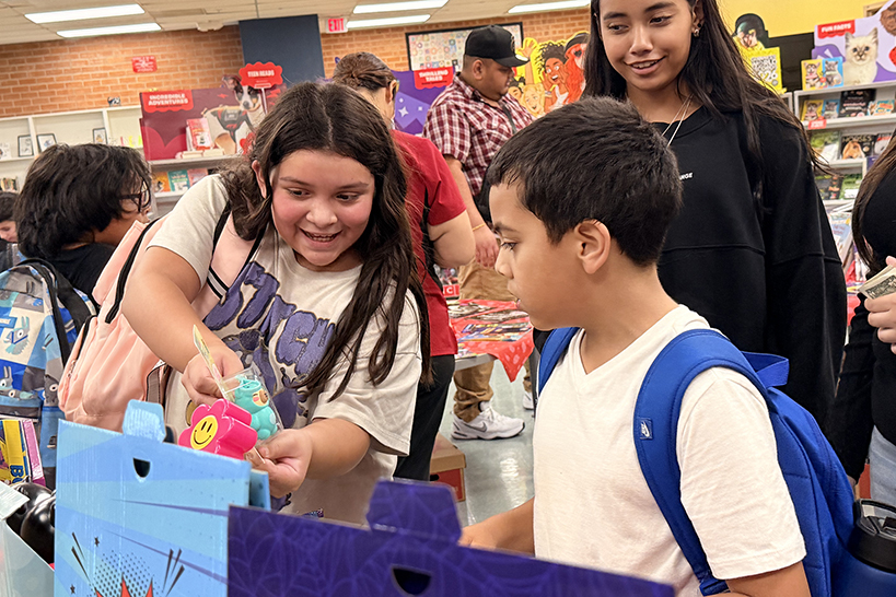 Two girls and a boy look excitedly at a book display