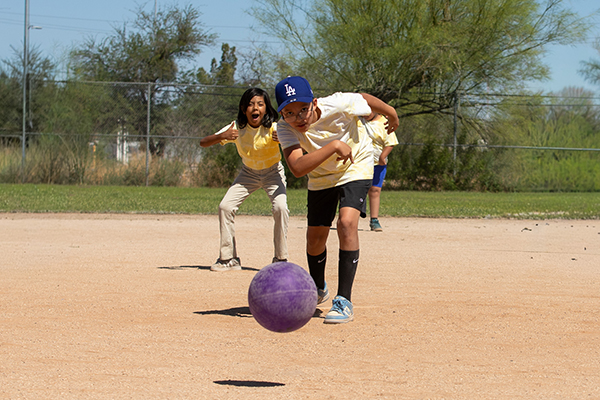 A boy tosses the purple kickball