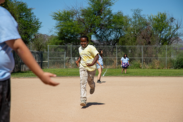 A boy in a yellow shirt runs around the field