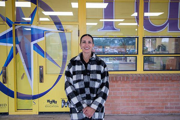 A woman in a black and white plaid jacket smiles in front of Tully
