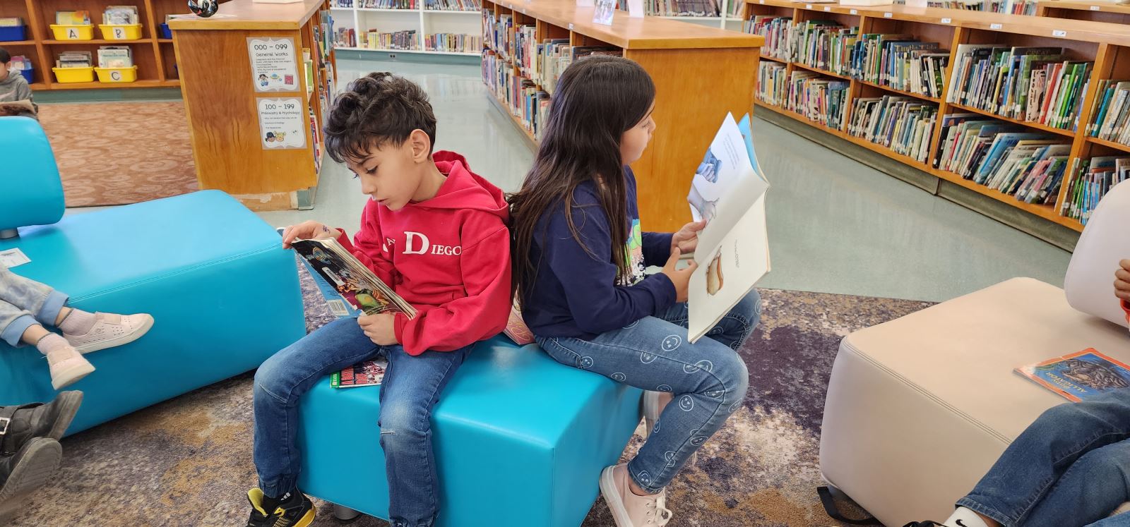 Two students sit back to back on a bench reading